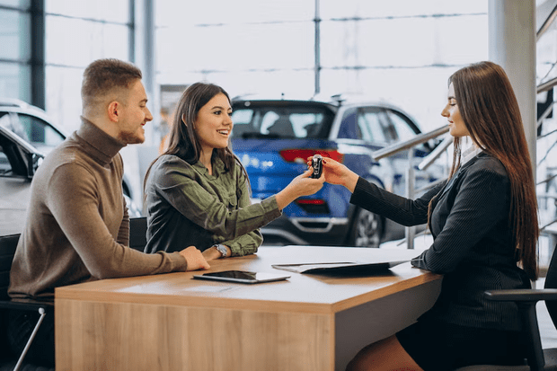 vendedora entregando chave do carro para casal 