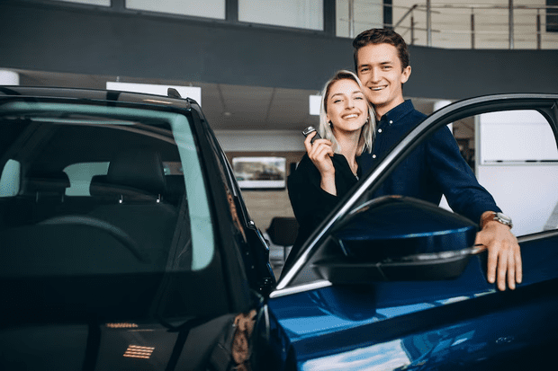casal segurando chave e ao lado do carro